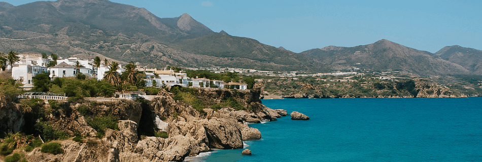 View of Nerja’s coastline with turquoise water, cliffs, and beach on a sunny day — perfect for a day trip from Málaga